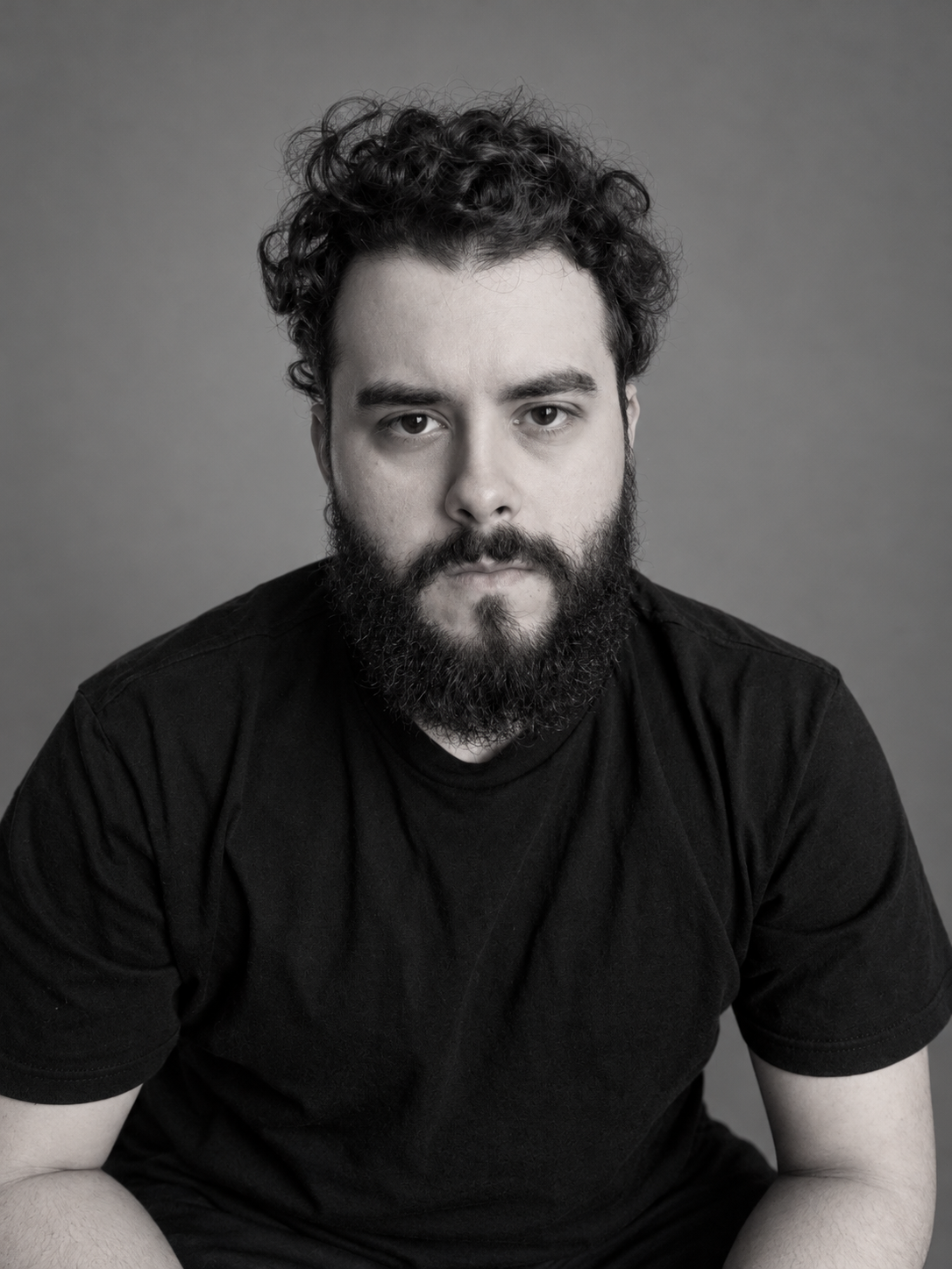Retrato de Adriano Barutti em preto e branco, de camiseta preta e olhando para a câmera.